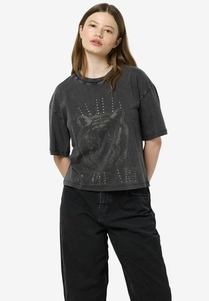 Black short-sleeve t-shirt featuring a textured lion graphic with metallic accents and bold lettering at the bottom; relaxed fit.
