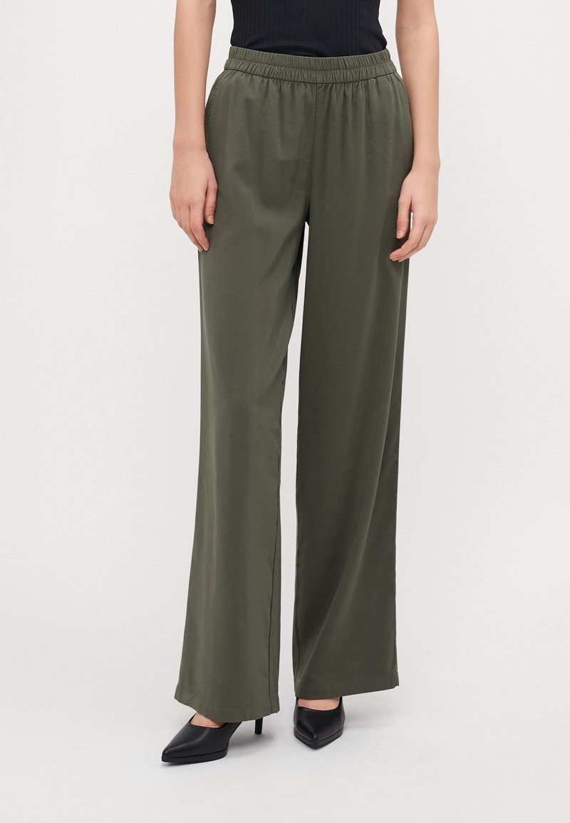 Olive green wide-leg pants made from a smooth, lightweight fabric with an elastic waistband. Paired with black pointed-toe heels.