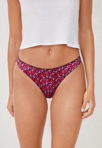 Costumi da bagno con motivo floreale in tonalità di rosa, blu e rosso, con un bordo in pizzo nero, caratterizzati da un design a vita bassa e copertura moderata.