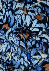 Blau- und schwarzes, abstraktes Blattmuster-Fabric mit strukturiertem Oberflächen; beinhaltet Schattierungen von Blau, Weiß und braunen Akzenten.