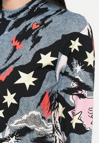 Dlhý rukáv s čiernym základom a farebnými vzormi hviezd a sŕdc v ružovej, žltej a červenej farbe. Tkanina má hladkú textúru.