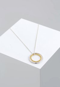 Sølv kædedyse med en dobbelt cirkulær vedhæng; en ydre glat cirkel og en indre snoet guldfarvet ring.