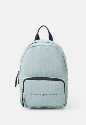 Light blue backpack made of textured fabric, featuring a front zip pocket, black zipper accents, and a top carry handle. Logo displayed on front.