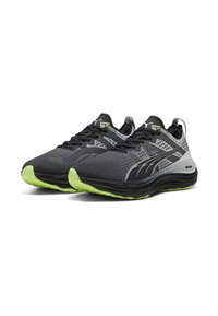 Scarpe da atletica nere e grigie con tomaia in rete, motivi testurizzati e suola in gomma verde. Presentano lacci e dettagli di marca.