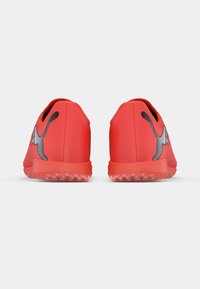 Røde atletiksko med en glat, mat tekstur, der har en sort logo og detaljer. Ydersålen har små fremspring for bedre greb.