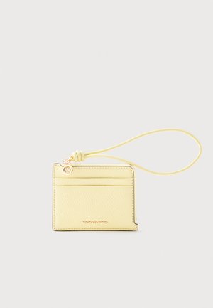 Bleekgele leren polshouder met drie kaartsleuven, een ritsvak en een gouden Michael Kors-logohanger met tekst.