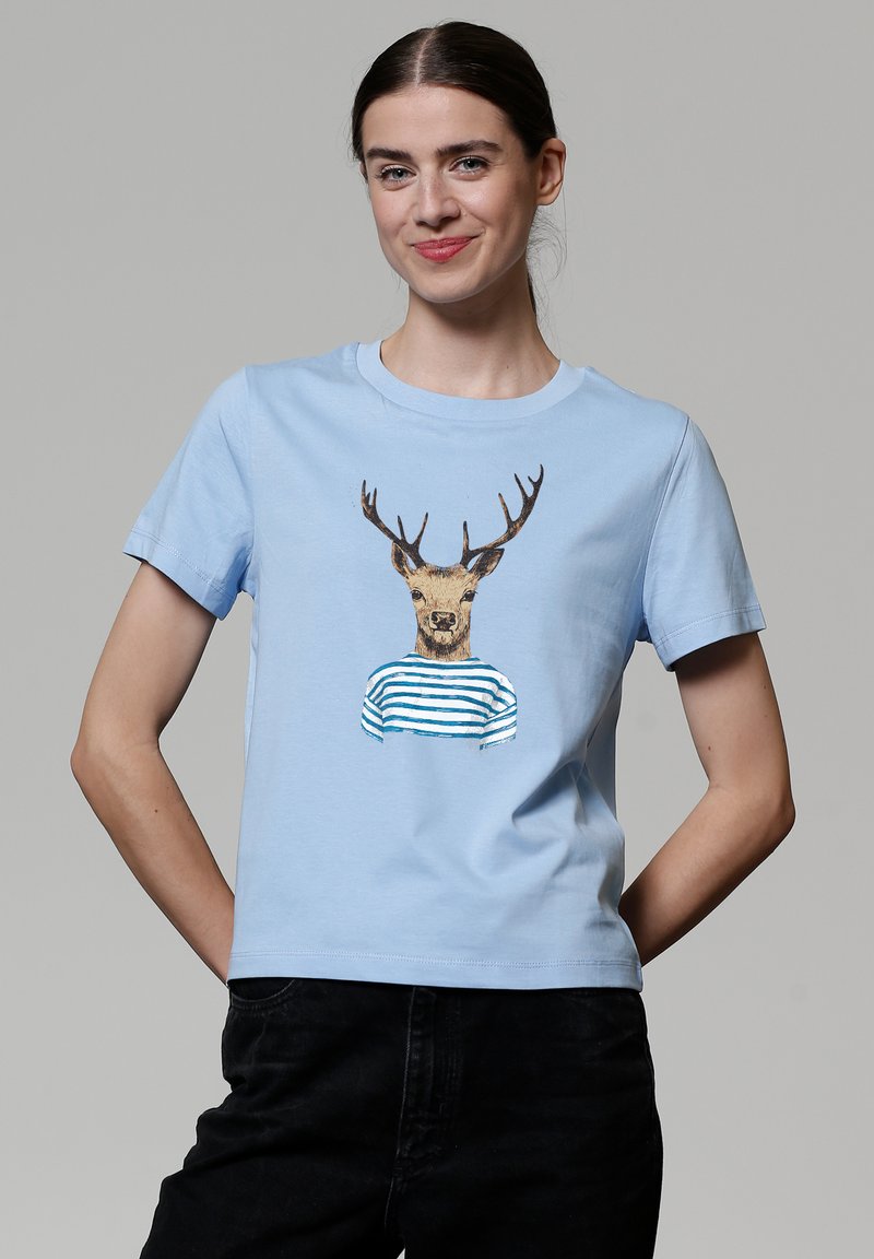 T-shirt en coton bleu clair avec un motif imprimé d'un cerf portant une chemise rayée. Manches courtes et col rond.