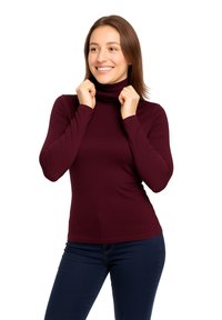 Maglione a collo alto bordeaux con maniche lunghe, design aderente, texture liscia e colletto alto, abbinato a jeans blu scuro.