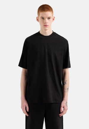 T-shirt nera a maniche corte realizzata in tessuto morbido, con scollo rotondo e sottili accentuazioni testurizzate sulle spalle.