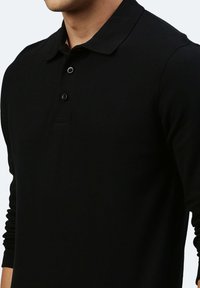Schwarzes Langarm-Polo-Shirt aus strukturiertem Stoff, mit klassischem Kragen und Knopfleiste mit drei Knöpfen, in enger Passform.