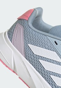 Zapatilla de malla gris con acentos blancos, tirador en el talón rosa, superposiciones texturizadas y una suela blanca acolchada que presenta la marca "Lightmotion".