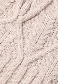 Material tricotat în bej moale cu un model texturat, având cabluri intercalate și linii delicate în zigzag, creând adâncime și interes vizual.