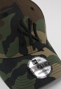 Verstellbare Tarnkappen mit schwarzem gesticktem NY-Logo, strukturiertem Design und einem glänzenden runden Etikett, das den 9FORTY-Stil anzeigt.