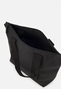 Borsa tote nera realizzata in tessuto resistente, con due manici robusti, chiusura con zip e un interno aperto senza scomparti visibili.