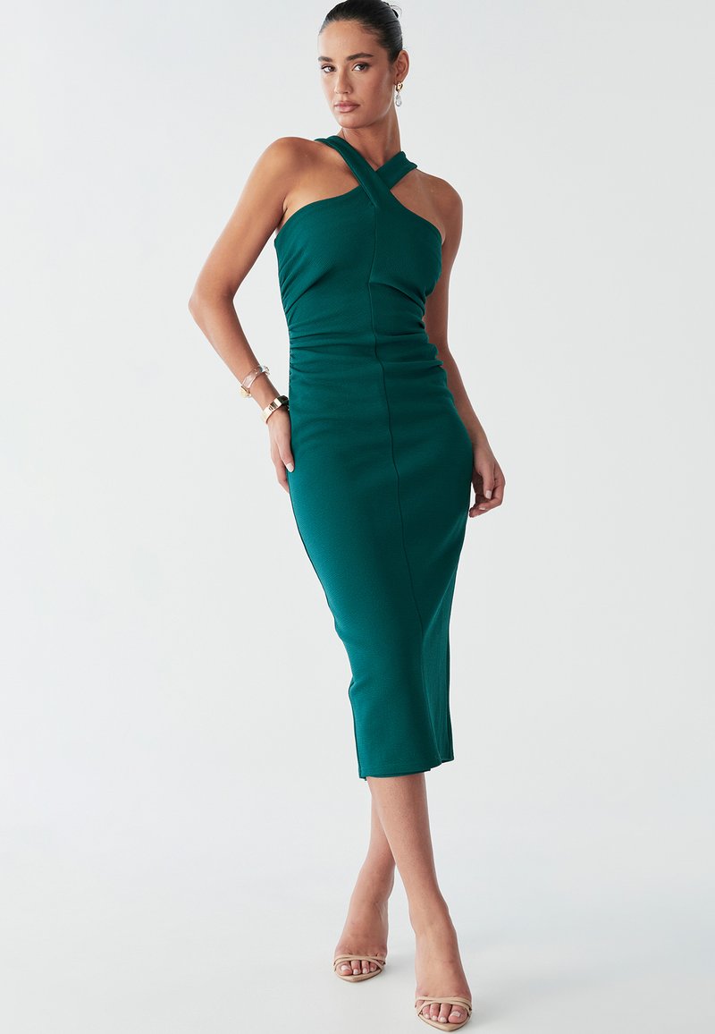 Vestido ajustado verde azulado con escote en cruz y detalles fruncidos, con un dobladillo a la altura de la rodilla y una tela texturizada.