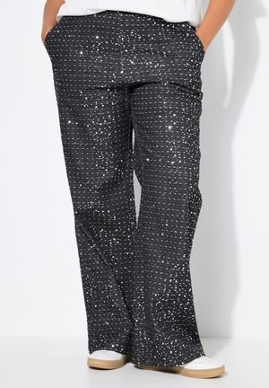 Schwarze Pailletten-Hosen mit weitem Bein, die eine strukturierte Oberfläche aus kleinen, glänzenden Pailletten und seitlichen Taschen aufweisen. Minimalistisches weißes Oberteil und Schuhe.