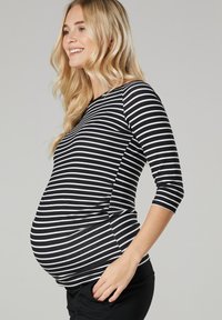 Schwarz-weiße gestreifte Umstandbluse mit Dreiviertelärmeln, taillierter Form und seitlichem Rüschendetail. Weicher, dehnbarem Stoff.