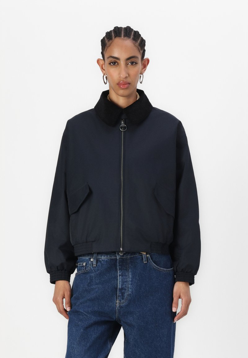 Black zip-up bomber jacket with a corduroy collar, elastic cuffs, and two front pockets. Worn with blue denim jeans.