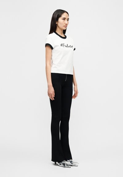 Λευκό μπλουζάκι με μαύρο περιθώριο, με λογότυπο "OFF-White", σε συνδυασμό με μαύρο παντελόνι φανελάκι και ασημί μυτερά παπούτσια.