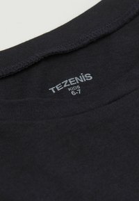 Černé bavlněné tričko s kulatým výstřihem. Vnitřní štítek zobrazuje "TEZENIS KIDS" a velikost "6-7". Tkanina vypadá měkce a texturovaně.