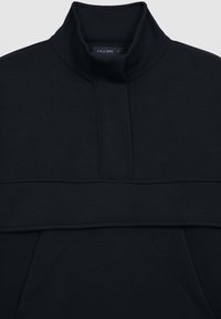 Pullover nero a collo alto con finitura testurizzata, caratterizzato da una cucitura sul petto e tasche laterali. Etichetta visibile all'interno del colletto.