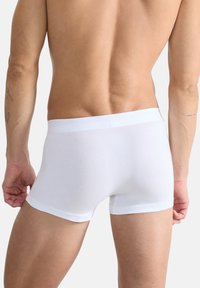 Weiße Baumwollboxershorts zeichnen sich durch eine glatte Textur und einen elastischen Bund aus, bieten ein passendes Design und minimierte sichtbare Nähte.