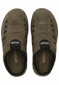 Braune Slipper mit einem strukturierten Lederoberteil, elastischen Seitenpanelen, schwarzen Akzenten und einem gepolsterten Innenfutter. Mit kontrastierenden Nähten.