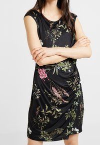Czarna sukienka w kwiaty z krótkimi rękawami. Posiada marszczony fason ozdobiony kolorowymi, botanicznymi wzorami w zieleni, różu i bieli.