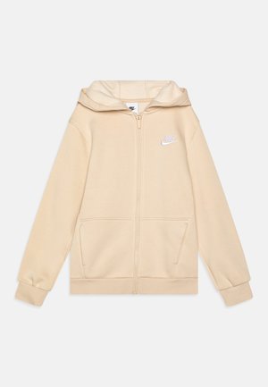 Sudadera con cremallera color beige, hecha de una tela suave y con capucha. Cuenta con dos bolsillos frontales y un pequeño logo blanco en el lado izquierdo del pecho.