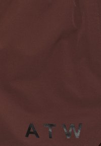 Brauner Stoff mit glatter Textur, auf dem ein schwarzes, gedrucktes "ATW"-Logo prangt. Die Kanten sind mit einer dezenten Naht versehen.