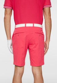 Rosa golfshorts i textilerad, med ett vitt bälte, två bakfickor och en skräddarsydd passform.