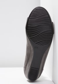 Scarpa in suede grigia con suola in gomma testurizzata, dotata di un sottopiede liscio e design ergonomico, con bordi curvi e indicazione della taglia.