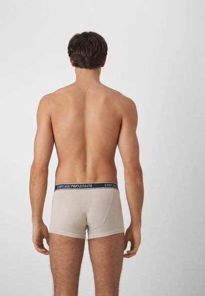 Beige boxerkalsonger i bomull, med en marinblå märkespanne. Designen inkluderar en åtsittande passform och en slät textur.