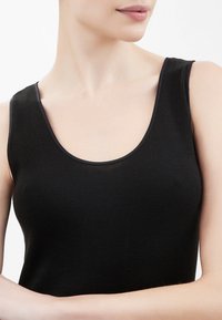 Top nero senza maniche, realizzato in tessuto a righe, con scollatura a barchetta e spalline larghe, dalla texture liscia e design minimalista.