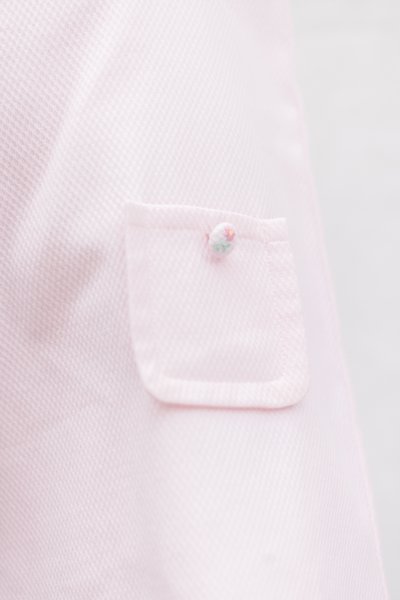 Ροζ ανοιχτό πουκάμισο με υφή υφάσματος, με μικρή τσέπη και διακοσμητικό κουμπί με λουλουδένιο σχέδιο.