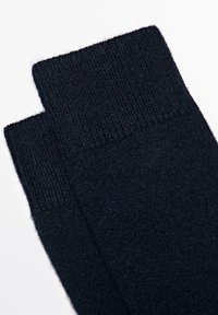 Calzini neri a maglia con un bordo a costine nella parte superiore, caratterizzati da una texture morbida e un corpo liscio, progettati per calore e comfort.