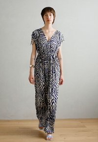 Jumpsuit long à manches courtes en imprimé zèbre blanc et marine, avec un décolleté en V profond et une taille froncée. Tissu lisse, coupe décontractée.