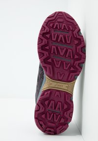 Semelle de chaussure de sport violette et noire présentant un motif texturé, un dessin de bande de roulement proéminent, et une section beige avec le logo ASICS.