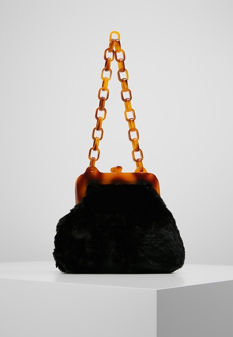 Černá plyšová kabelka s řetízkem a zavíráním z jantarového želvovinového vzoru. Měkká textura, zaoblený tvar a strukturální horní rám.