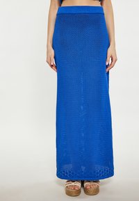 Gonna maxi blu lavorata a maglia con texture a trama aperta. Presenta una cintura larga e una silhouette dritta, che arriva fino alla caviglia.