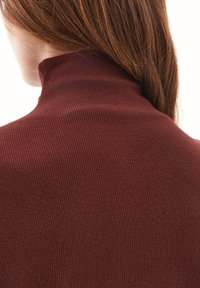 Ribbet turtle-neck top i dyb burgunder. Stoffet er tekstureret og tætsiddende, med en høj krave og en glat finish.