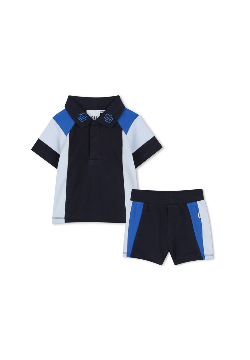 Polo blu navy con dettagli azzurri e blu royal, maniche corte e pantaloni corti abbinati con un design a blocchi di colore simile.