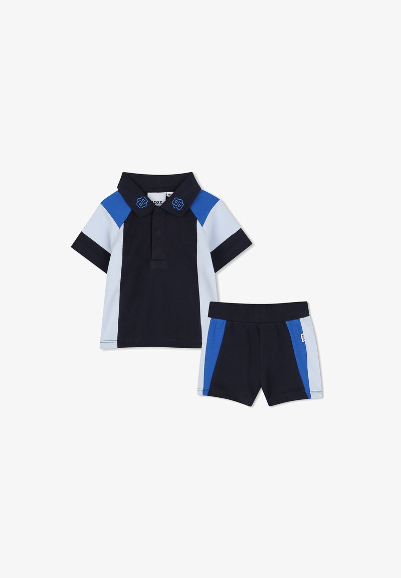 Polo blu navy con dettagli azzurri e blu royal, maniche corte e pantaloni corti abbinati con un design a blocchi di colore simile.