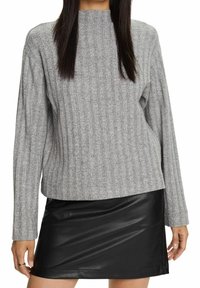 Harmaa raidoitettu neulepaita, jossa on korkea kaulus ja pitkät hihat, yhdistetty mustaan tekonahkasta valmistettuun mini-hameeseen. Kangas näyttää teksturoidulta ja mukavalta.