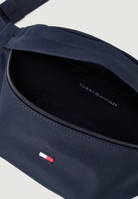 Jūrų jėgos audinio per petį nešiojama krepšys su užtrauktuku, vidiniu prekės ženklu ir mažuoju raudonos, baltos ir mėlynos spalvų logotipu. Lygi tekstūra.