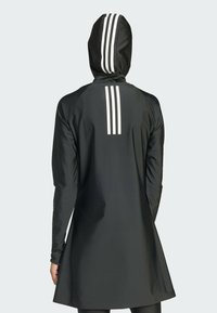 Vêtement à capuche noir avec trois bandes verticales blanches dans le dos, fabriqué en tissu lisse et flexible, de coupe mi-genoux.