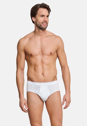 Weiße Baumwollslips mit glatter Textur, elastischem Bund und klassischem Schnitt, präsentiert an einem männlichen Modell vor neutralem Hintergrund.