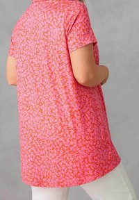 Krátký rukáv, horní část ve světlé růžové barvě s květinovým vzorem, vyrobená z měkké látky. Mírně volný střih, spodní okraj s prošitým zakřivením.