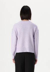 Pull léger en lavande avec une coupe décontractée, ourlet et poignets côtelés. Fabriqué en matériau doux et texturé, il présente des épaules tombantes.