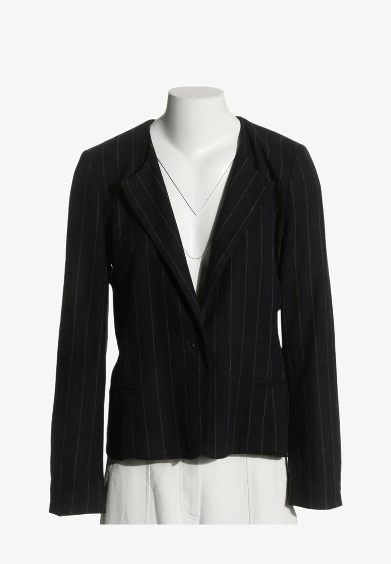 Blazer noir à fines rayures avec fermeture à un bouton, présenté sur un mannequin sans tête portant un pantalon blanc.